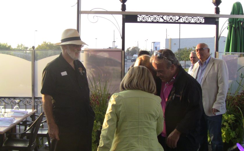 group of people gathered, entry way with two tall lamps, green closed patio table umbrella